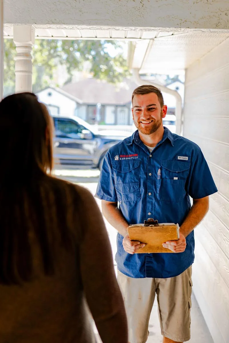 Custom Air Conditioning Air Quality technician smiles while speaking with a customer at her front door