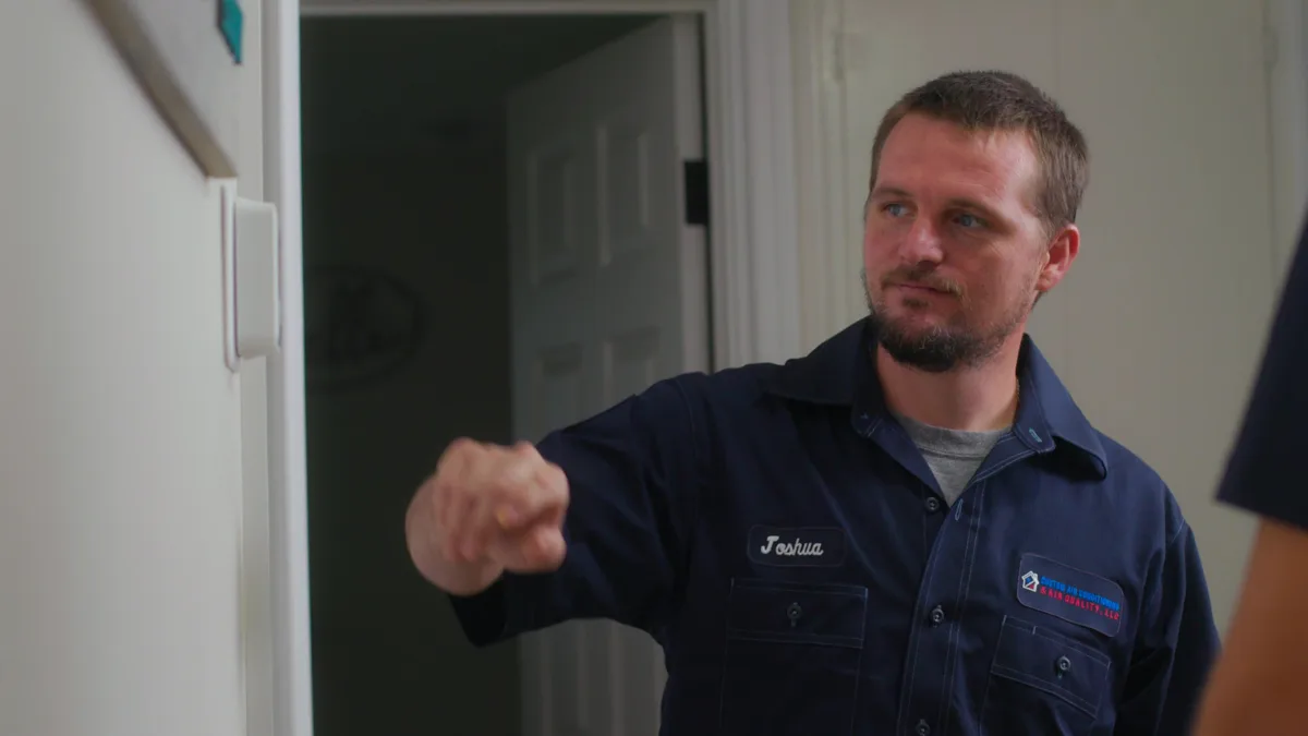 Custom air conditioning and air quality technician fine tuning thermostat settings during a service visit
